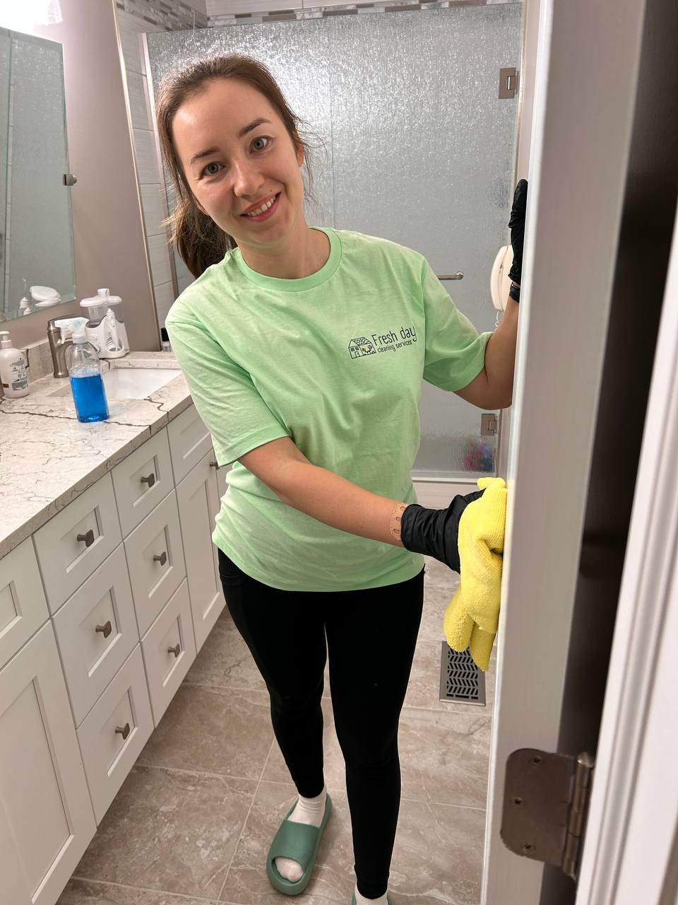 a woman in a green shirt is cleaning a bathroom