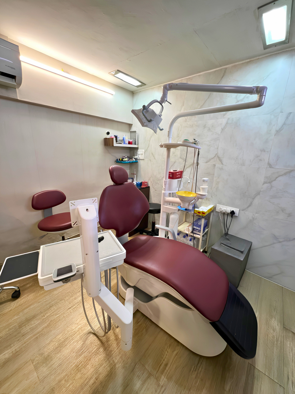 Modern dental clinic interior featuring a maroon examination chair and professional dentistry equipment.