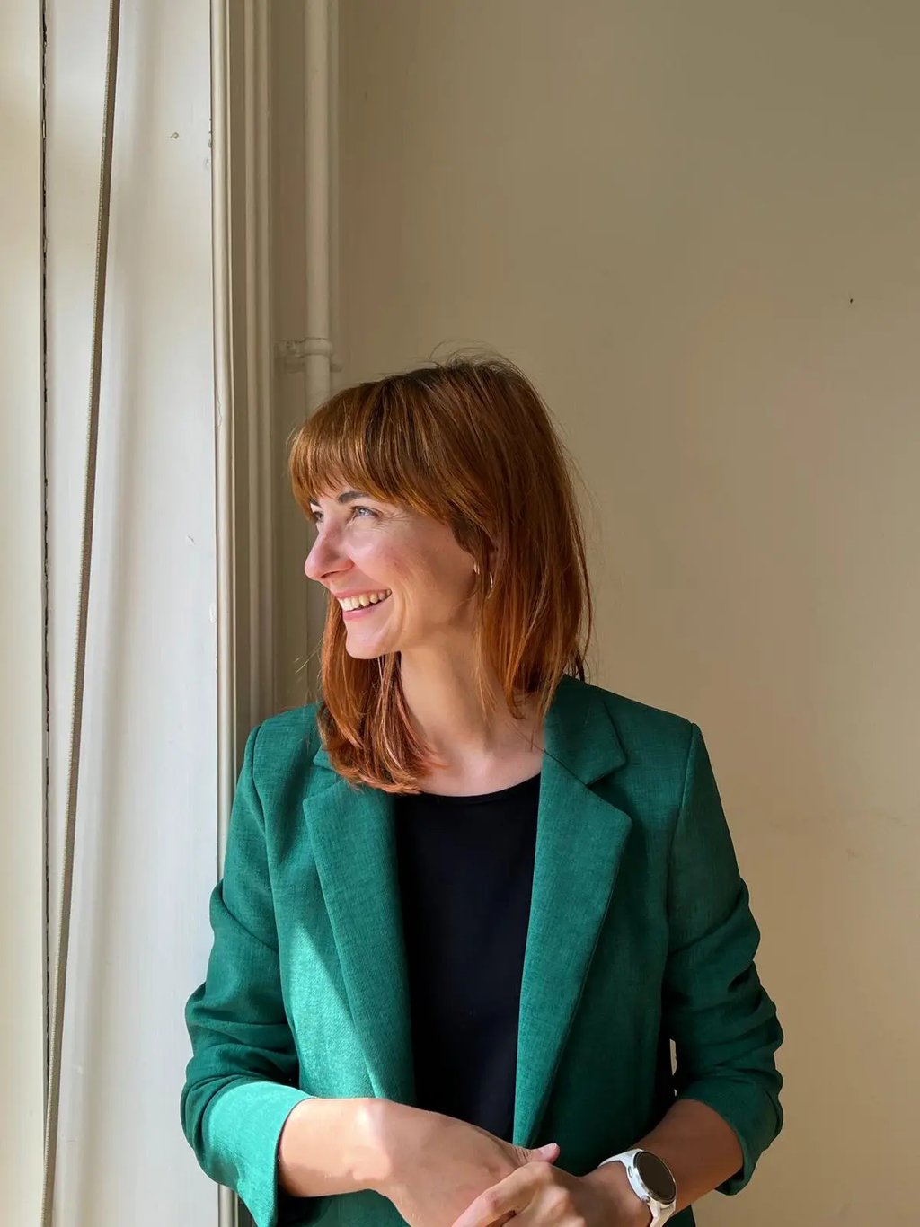 A smiling woman in a green blazer looking to the side, representing a client after an RTT session