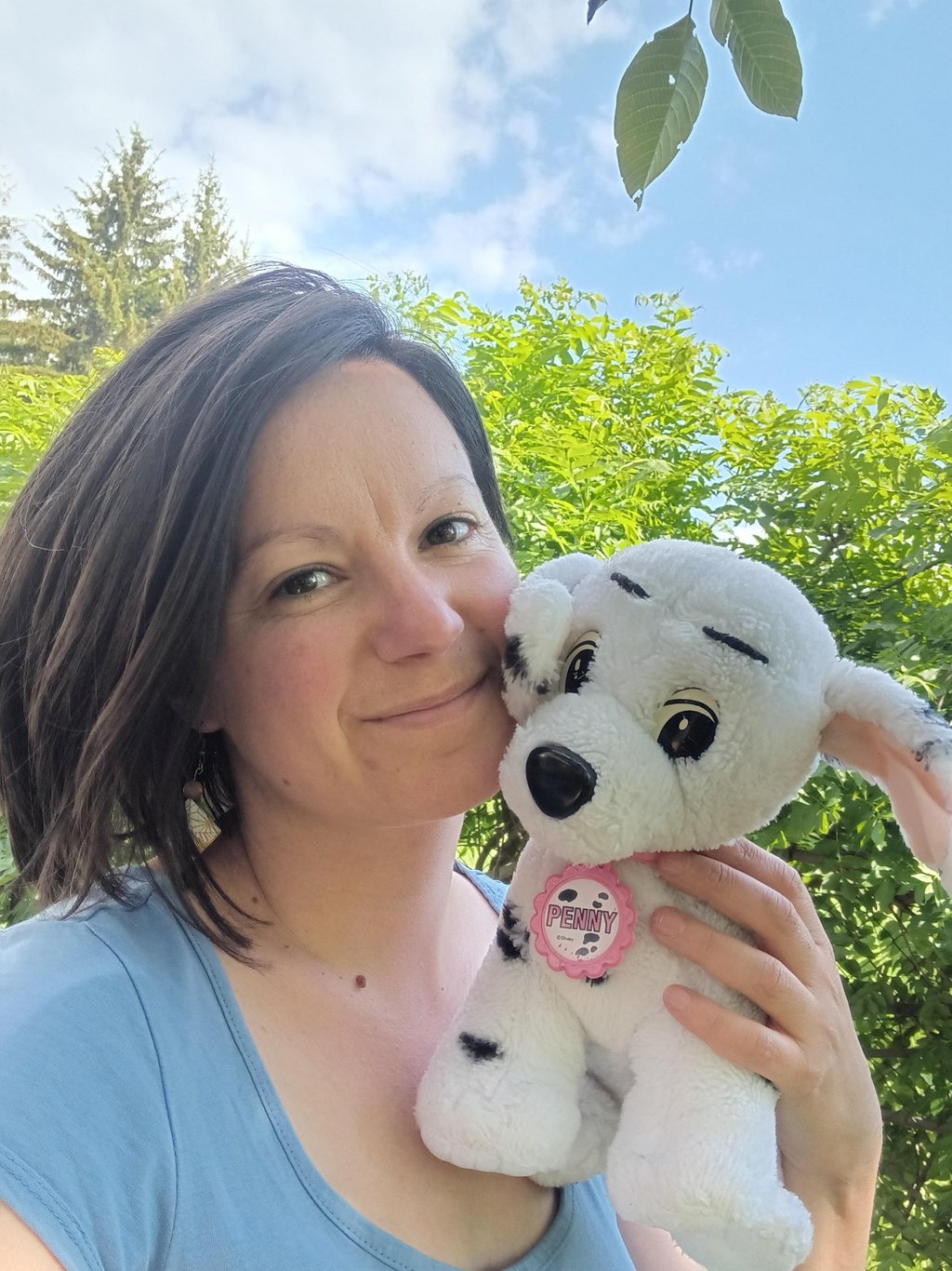 Natacha Rossignol tenant sa peluche d’enfance Penny dans un jardin ensoleillé des Hautes-Alpes