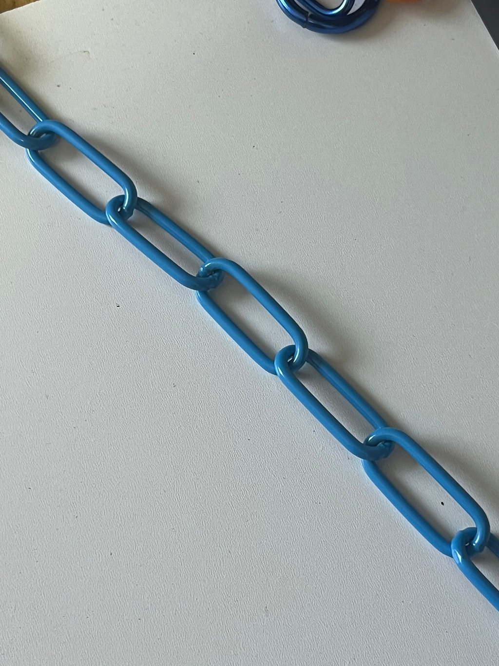 Runder Kreis mit einem Farbmuster mittig eine Kette in Blau, Hundekette, Pulverbeschichtet