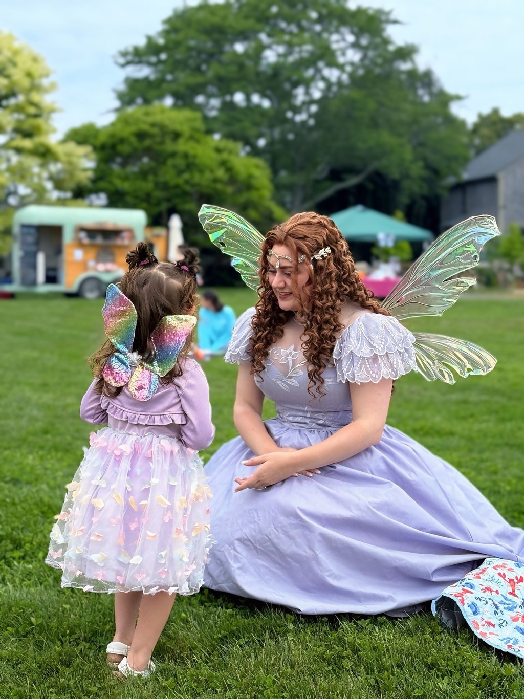 Purple fairy smiles at a kid also dressed as a fairy