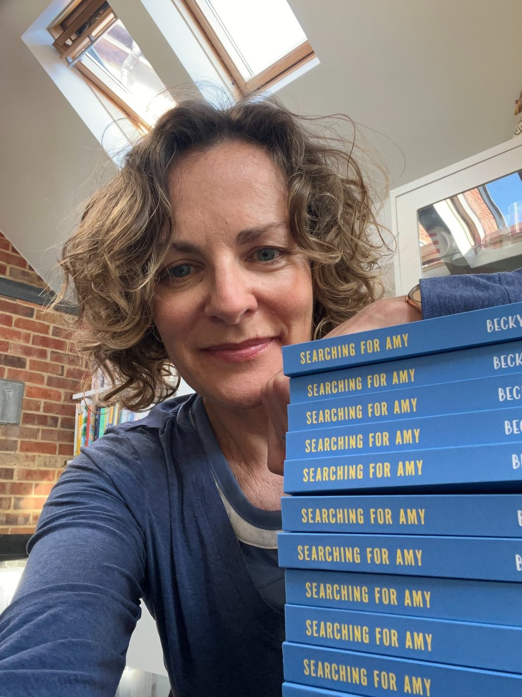 author with a pile of copies of Searching for Amy