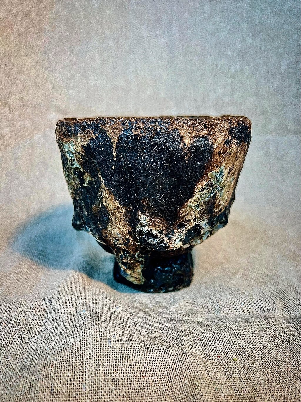 Handmade wabi-sabi ceramic tea bowl with a dark rustic glaze and textured finish.