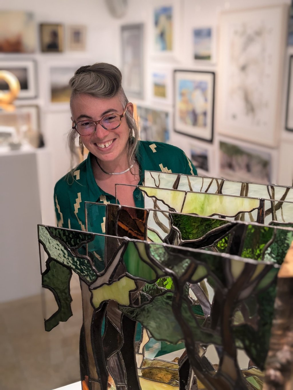 Image of Artist Laura Kriefman at Biennale Exhibition opening. Laura is smiling and looking at her bespoke glass art