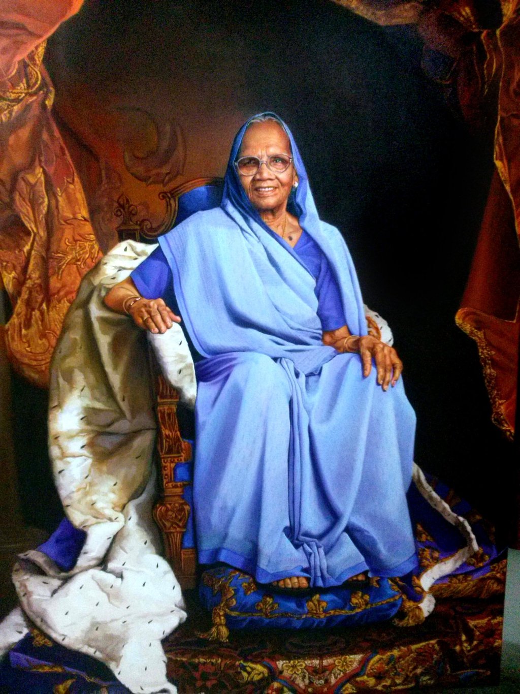 an oil on canvas portrait depicting an old Indian woman wearing saree sitting on a royal chair