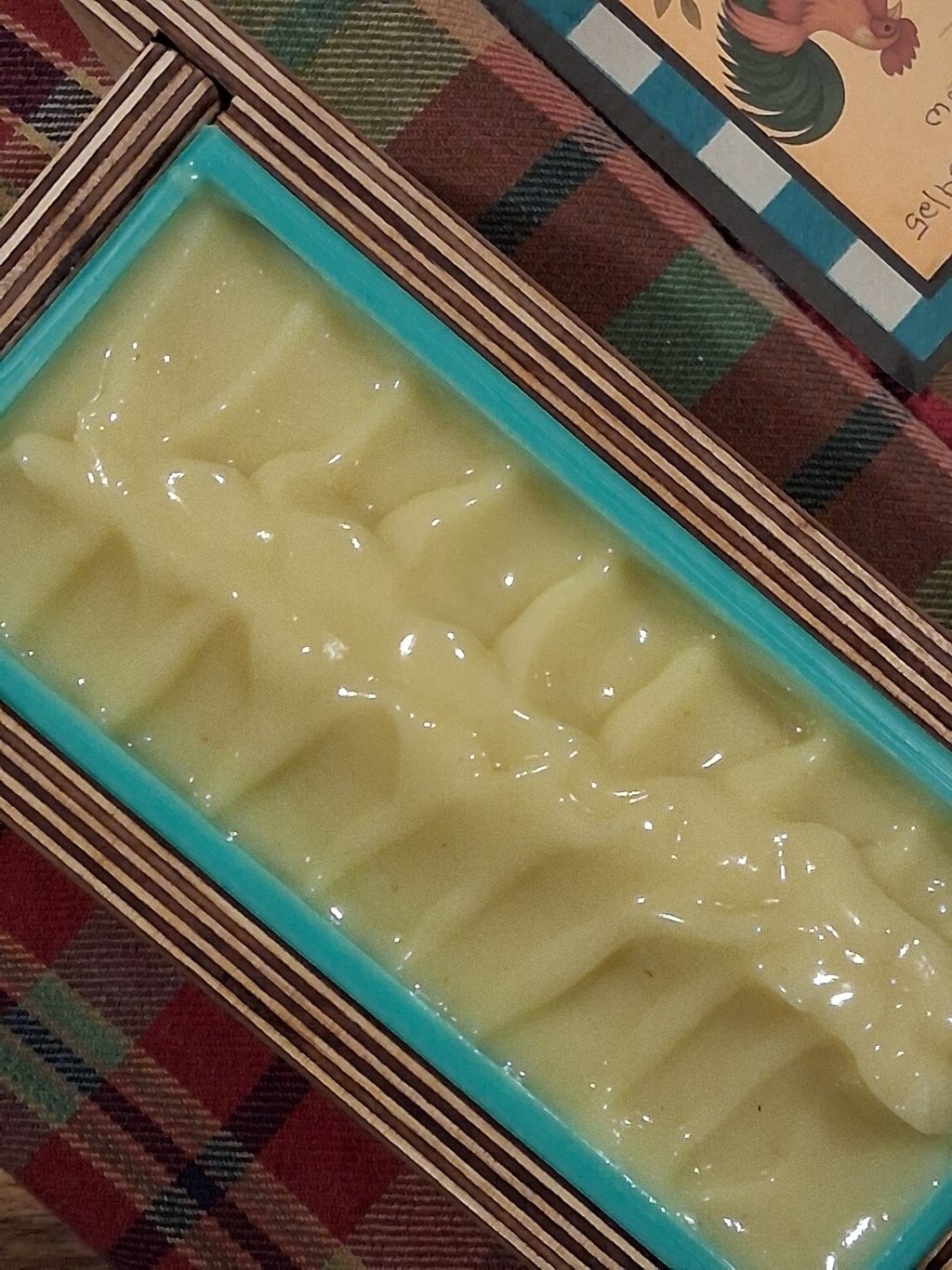 Freshly poured yellow handmade soap batter in a silicone loaf mold with a wooden frame.