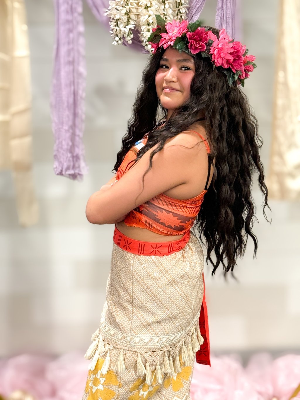 Girl in Moana with long wavy hair, a pink flower crown, and traditional Polynesian style clothing.