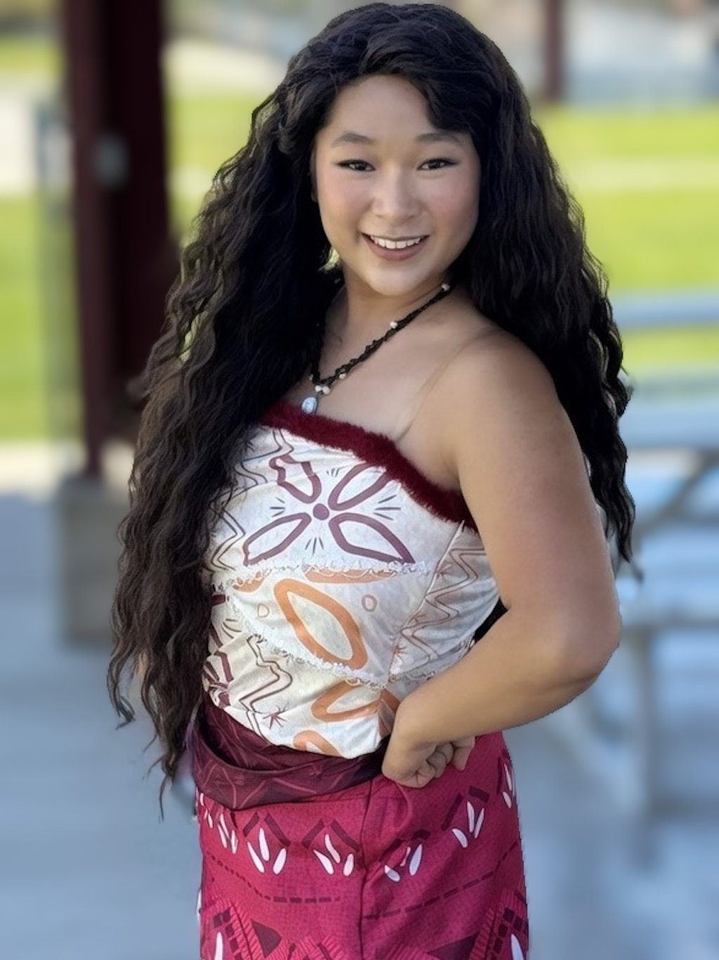A girl in a Moana costume with long curly hair and a patterned Polynesian dress.