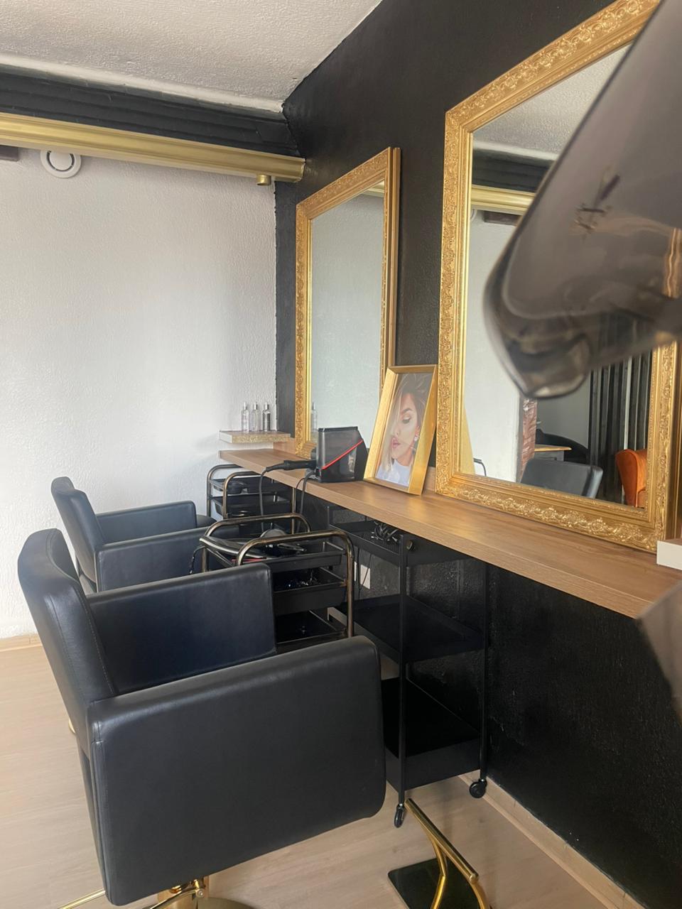 Vue intérieure du salon X Tension NC avec fauteuils professionnels et miroir doré, un espace dédié à