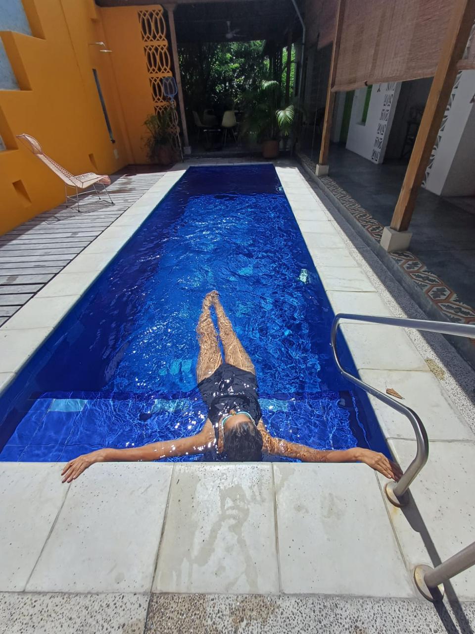 A woman floating in a luxury outdoor lap pool with deep blue water at a tropical villa.