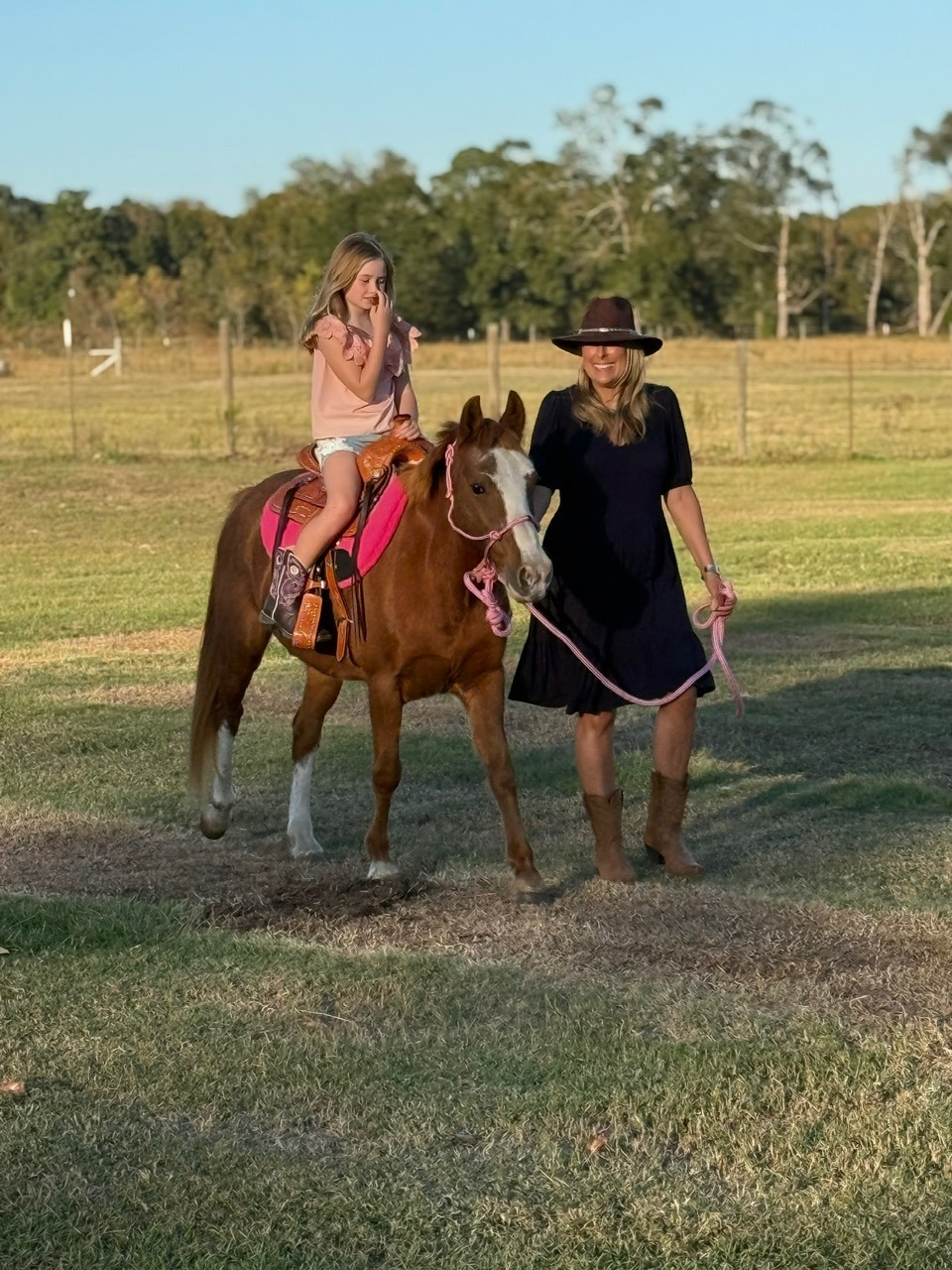 Pony Party owner hand leading Snickers the pony while a child rides