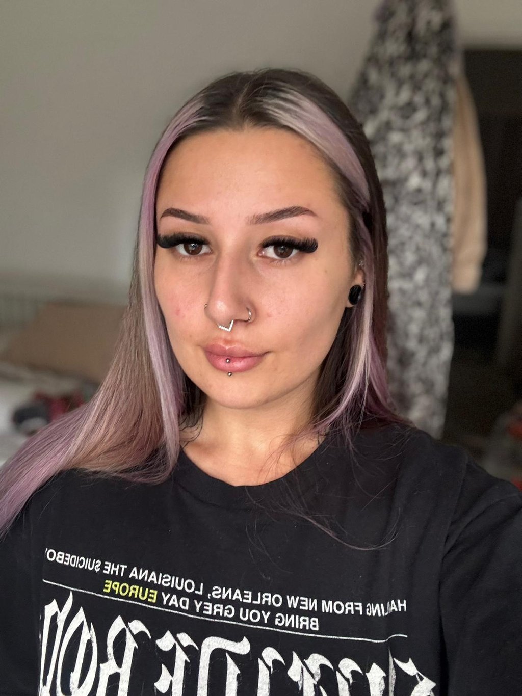 Woman with purple dyed hair and facial piercings wearing long volume eyelash extensions.