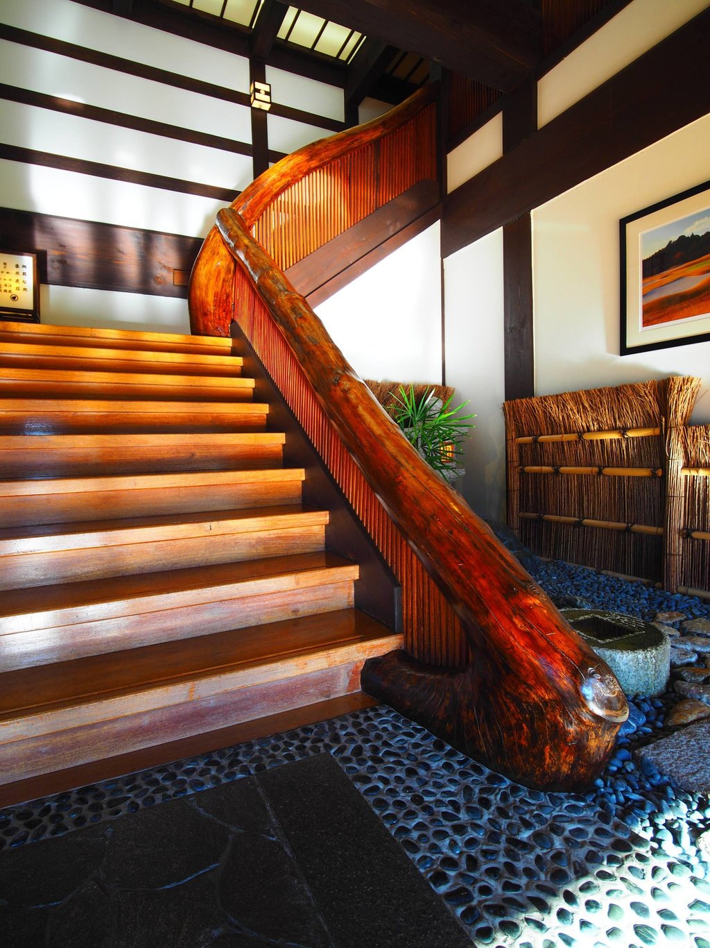 Traditional Japanese interior featuring a polished wood staircase with a curved natural log handrail.
