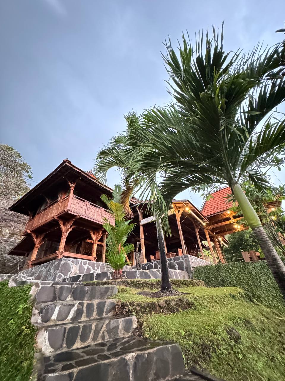 Joglo pavilion placed in tropical garden environment blending antique teak architecture with natural landscape