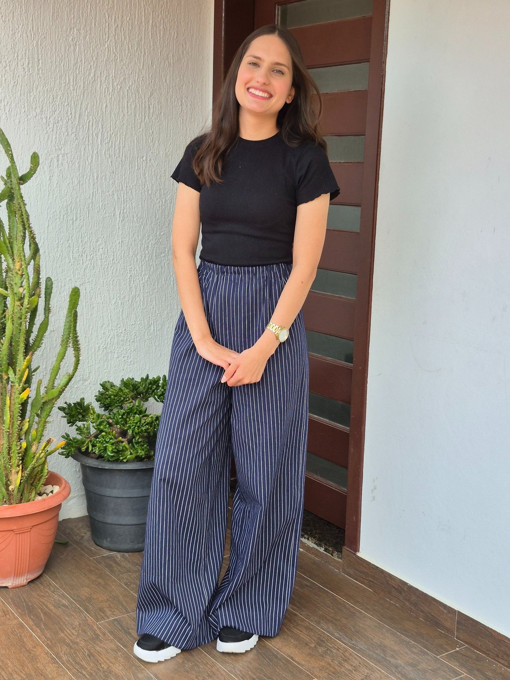 Mulher em pé uma calça azul marinho com estampa risca de giz