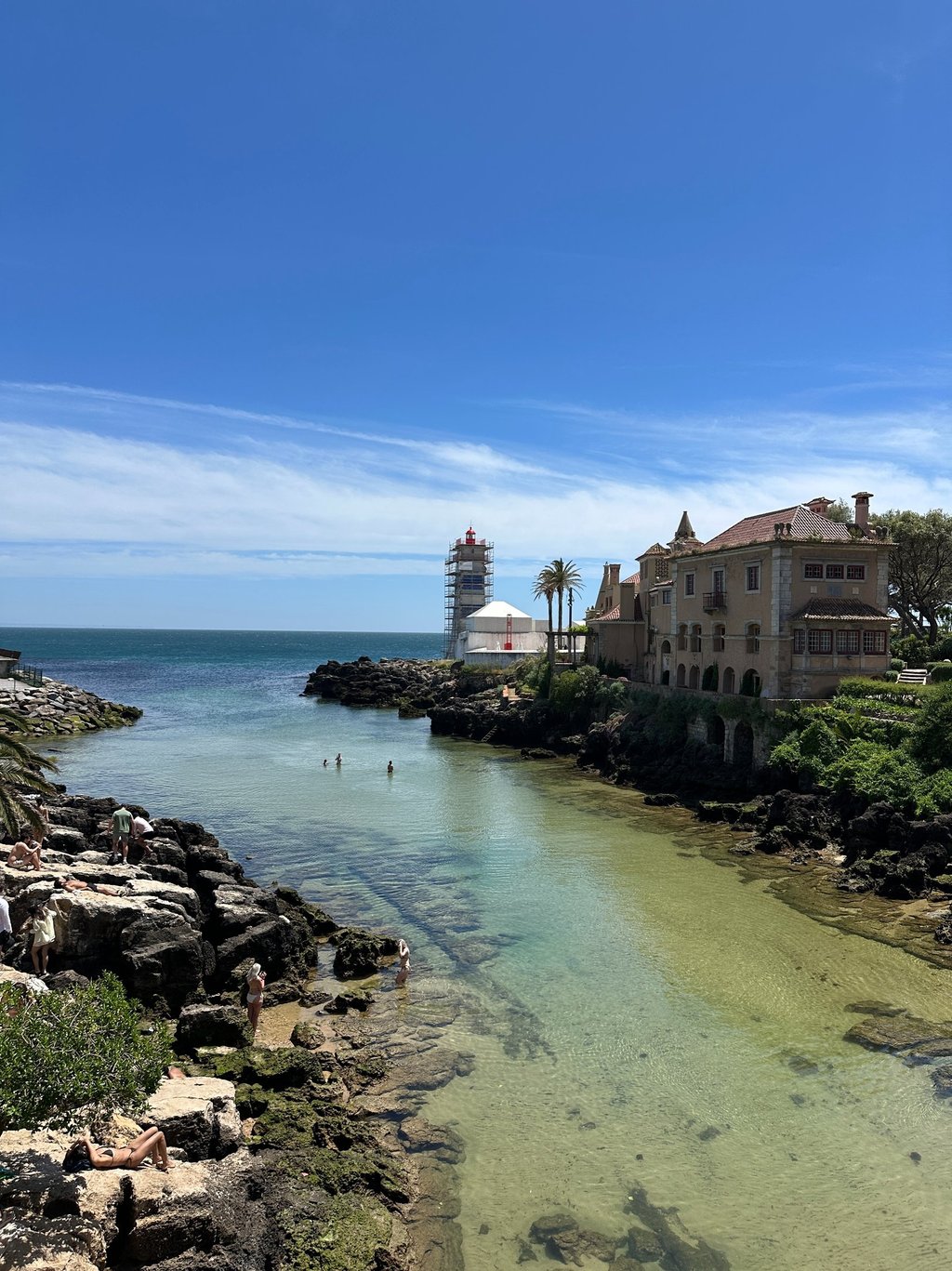 Águas critalinas com uma casa e um farol ao fundo