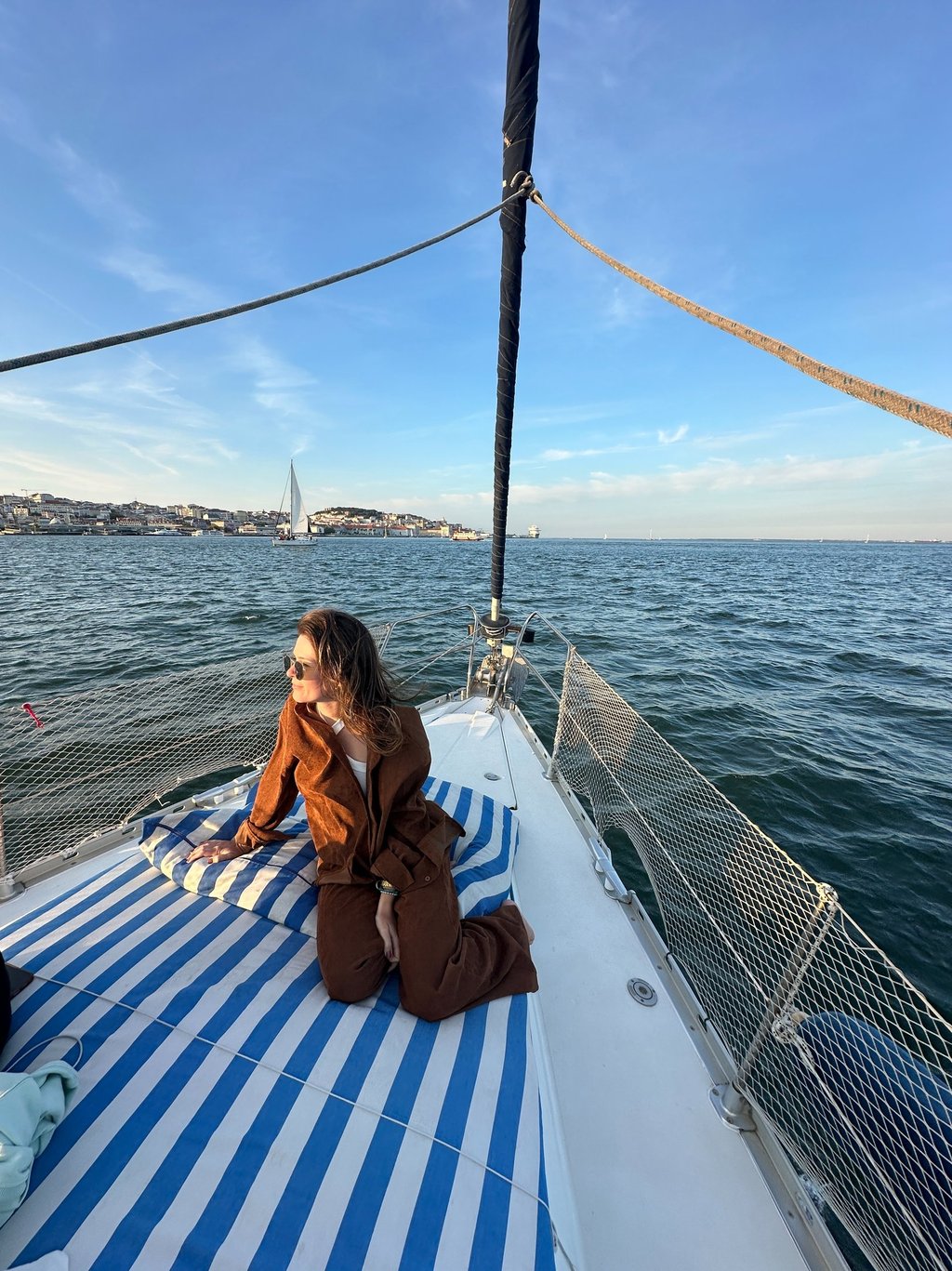 Pessoa sentada na ponta do barco, com a agua ao fundo