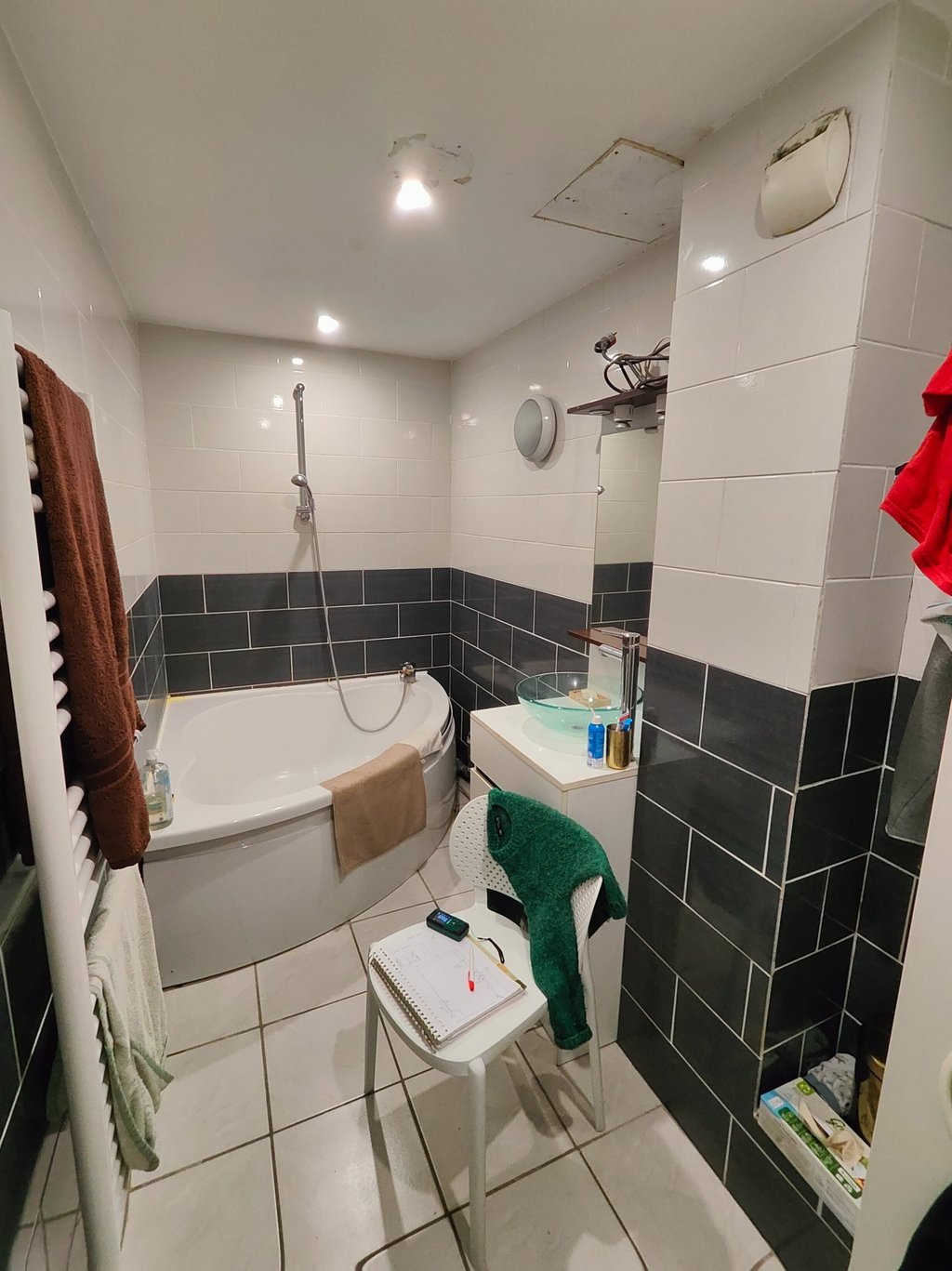 salle de bain avec baignoire d'angle et carrelage gris et blanc aux murs