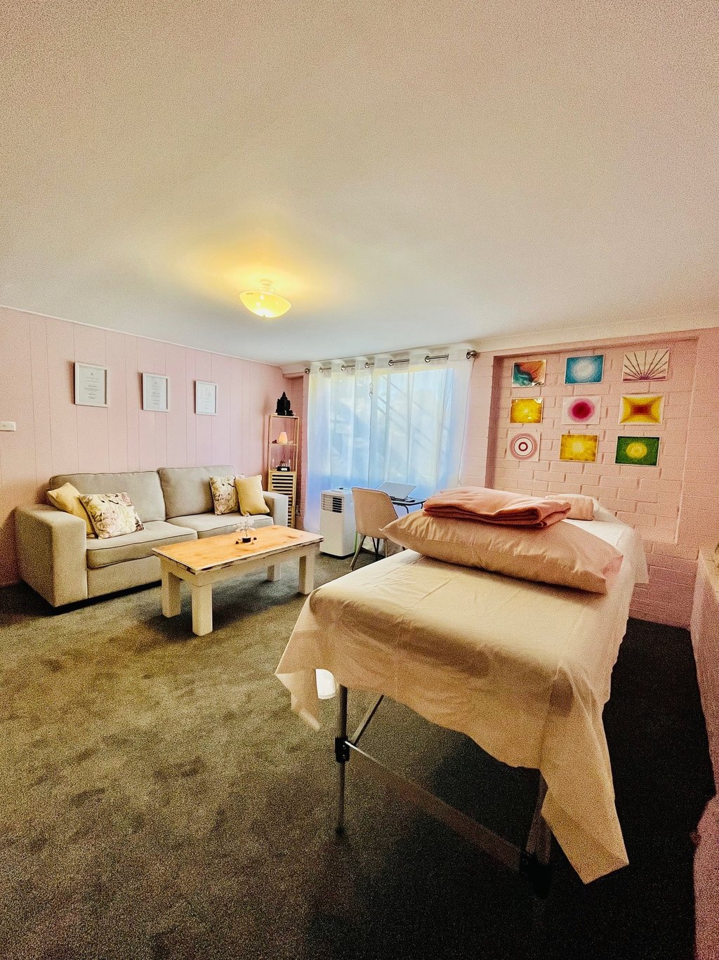 healing room with table, couch and massage table in pink