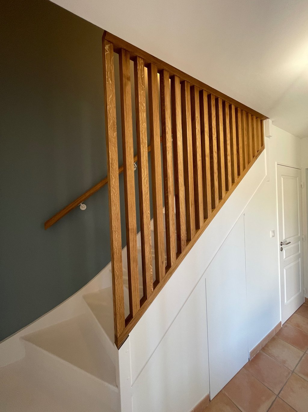 a staircase with a wooden handrail and a door