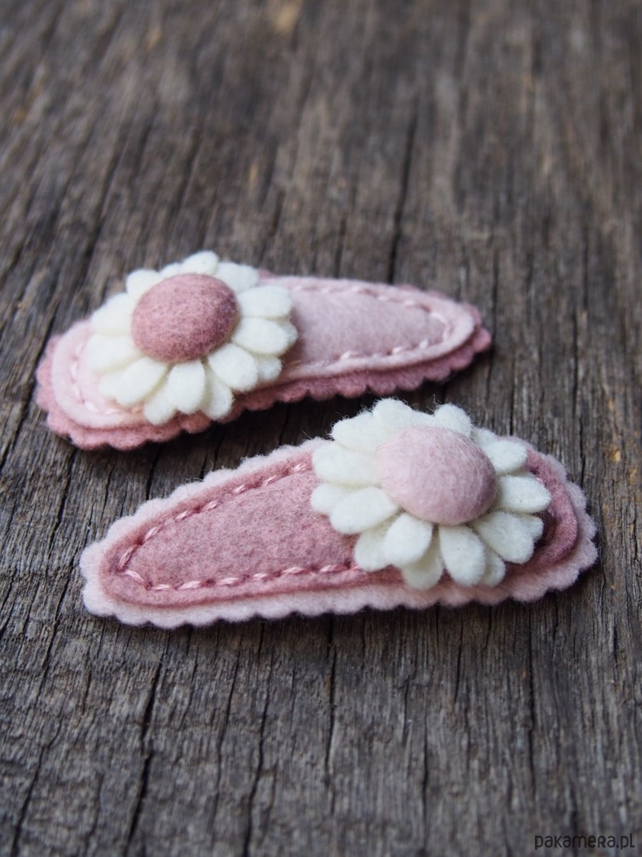 różowe spinki z białym kwiatkiem na tle drewnianej deski