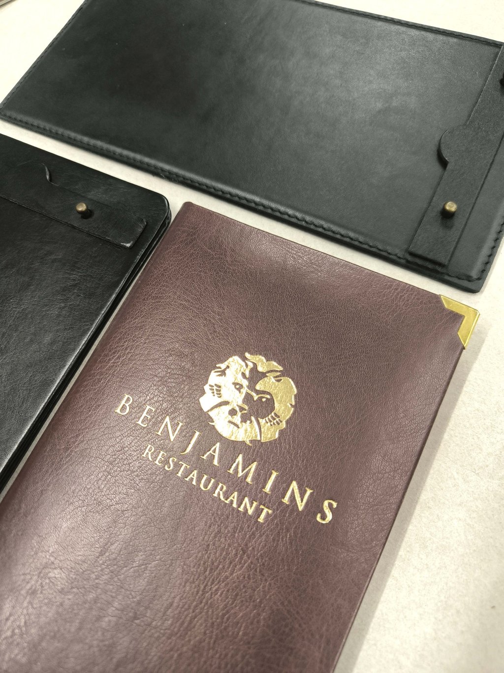 Custom leather menu covers and check presenters with gold foil restaurant logo.