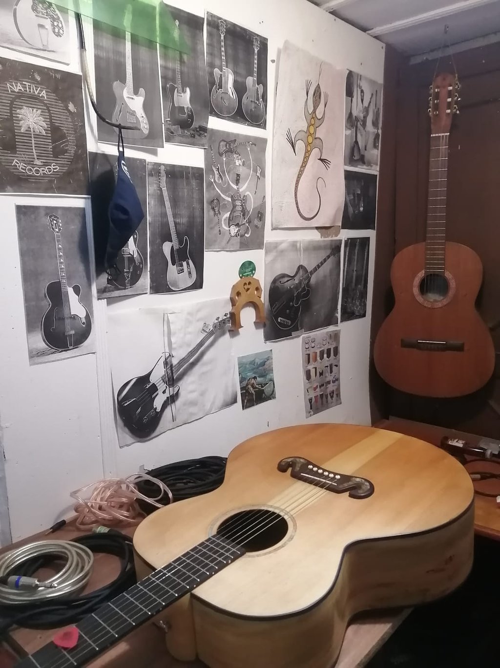 Guitarra acústica sobre un banco de trabajo de luthería, con bocetos de guitarras y herramientas  
