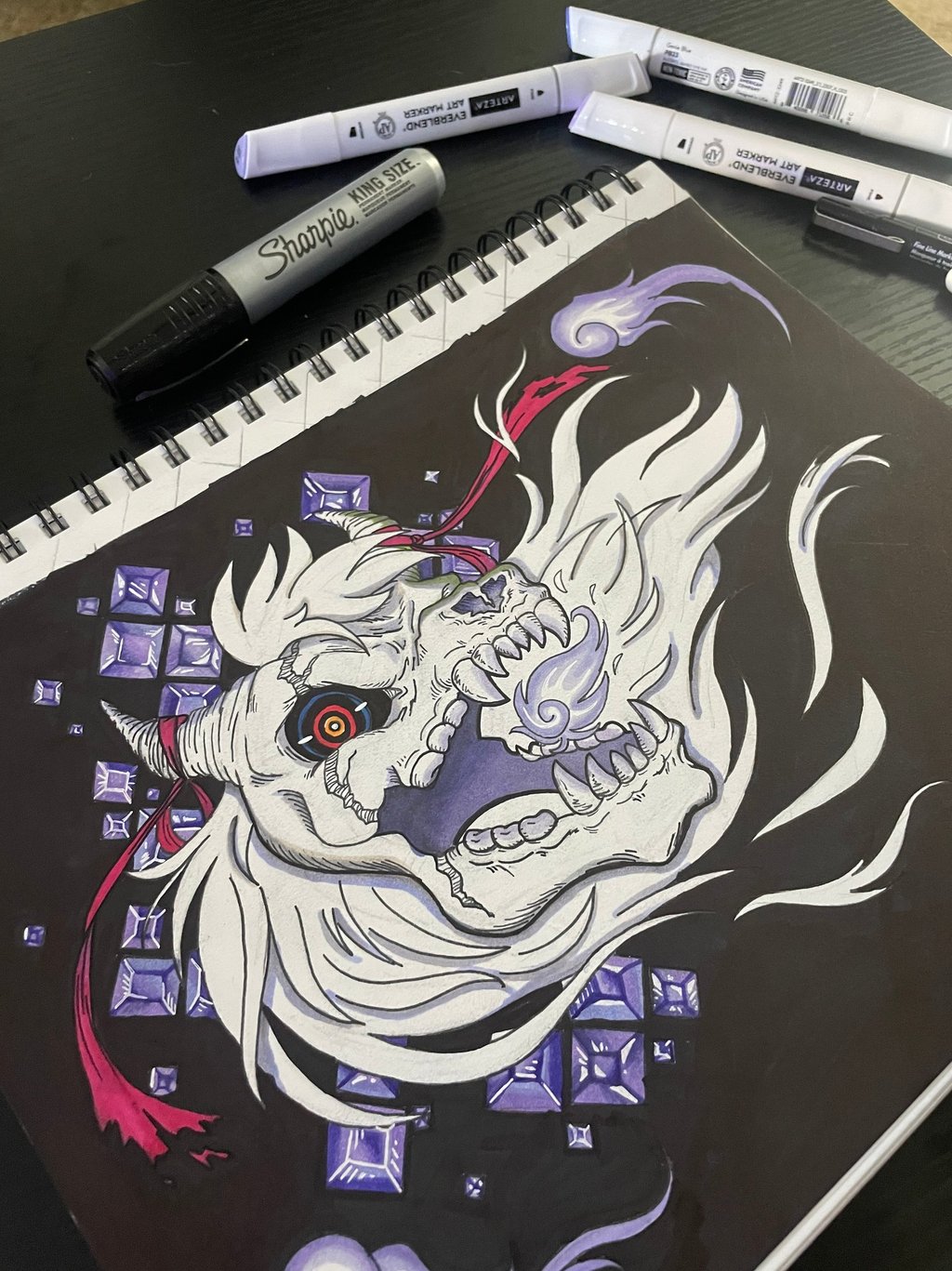 a marker on sketchpad drawing of a demon creature with purple gems and red straps 