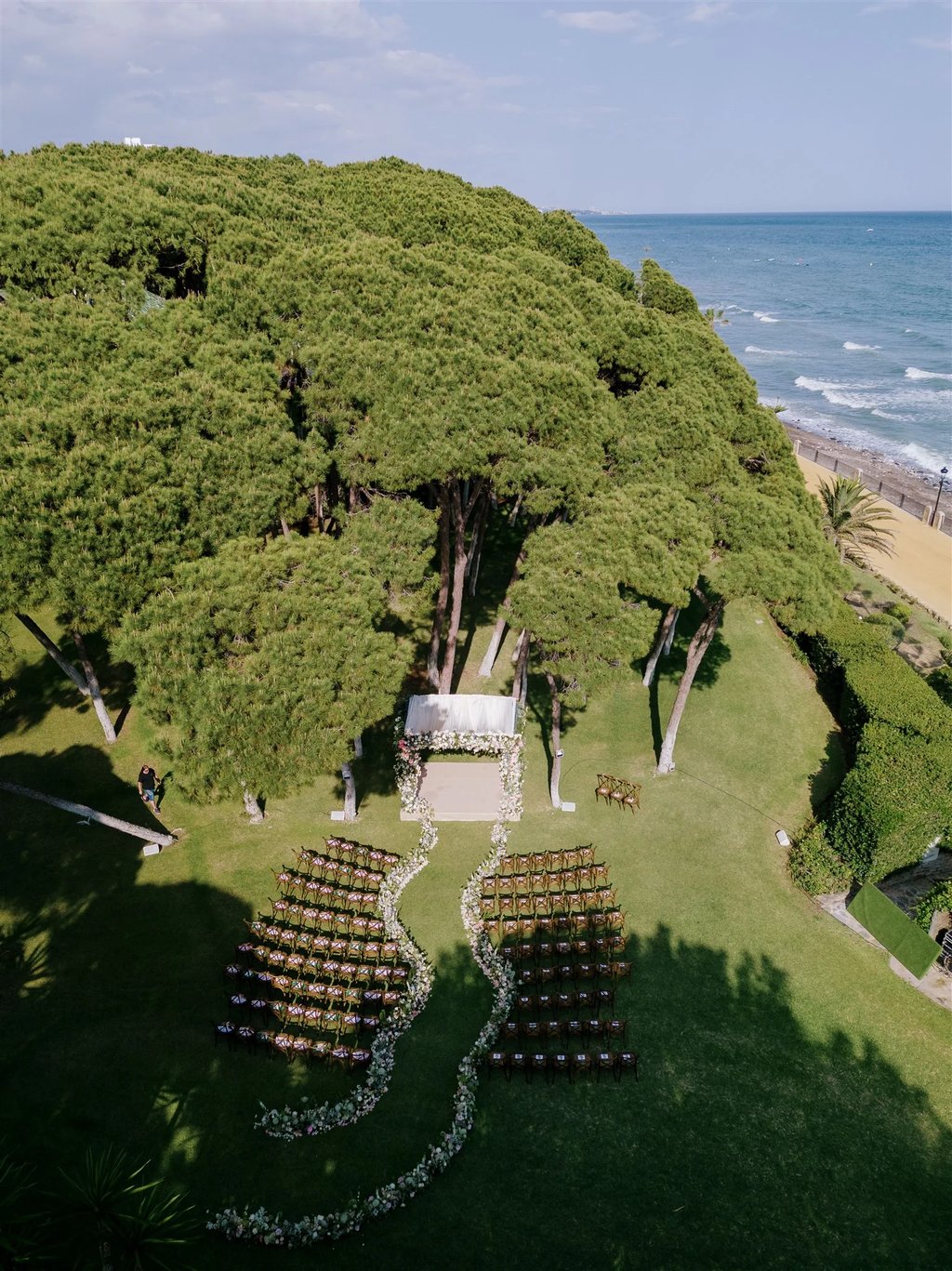 Outdoor wedding ceremony setup under pine trees by the sea