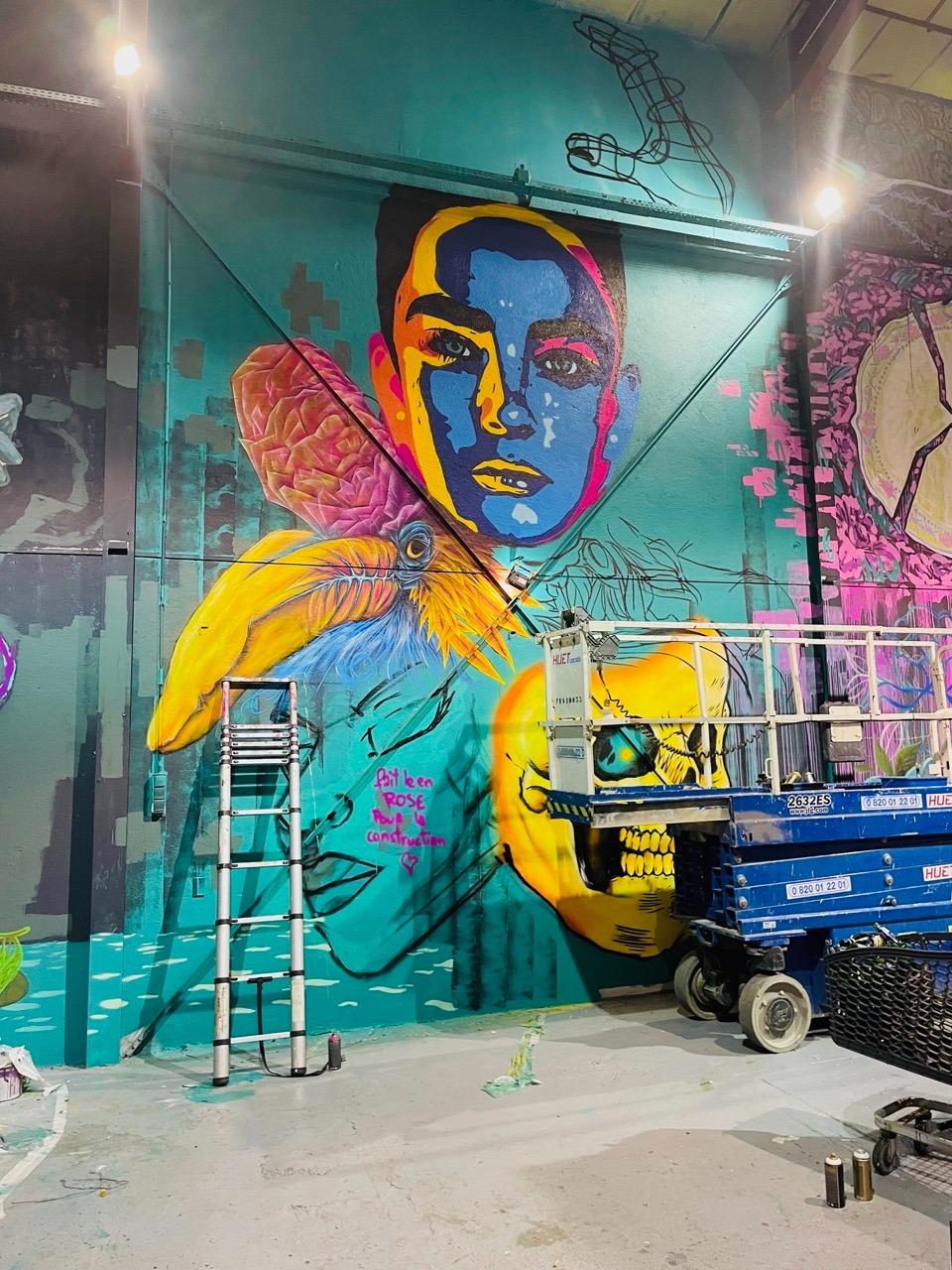 une fresque en cour de création avec une nacelle et une échelle