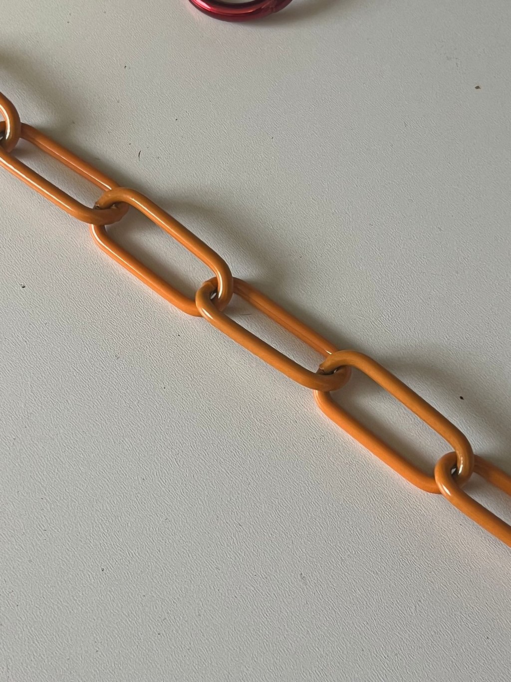 Runder Kreis mit einem Farbmuster mittig eine Kette in Orange, Hundekette, Pulverbeschichtet