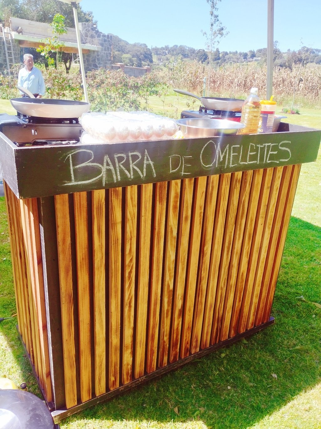 Outdoor wooden omelette bar station with fresh eggs and frying pans for event catering.