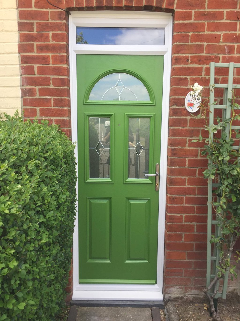 a bespoke bright green front door with diamond lead glass.  there are three windows on the door 