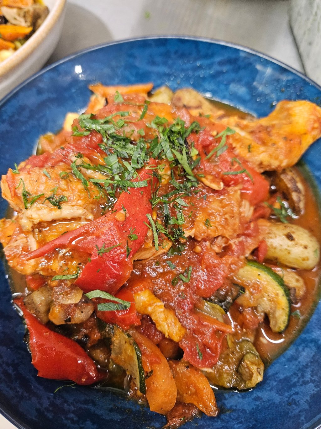 Cacciatore au poulet cuit lentement avec des poivrons rouges, des courgettes et de la sauce tomate.