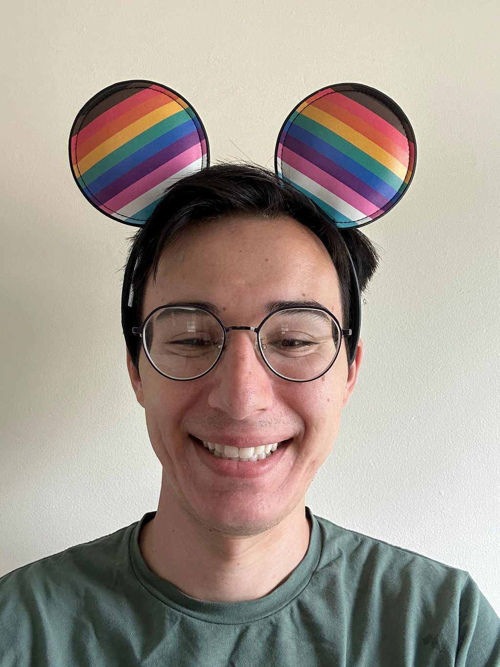Travel Agent Andrew, wearing rainbow pride mouse ears and smiling.