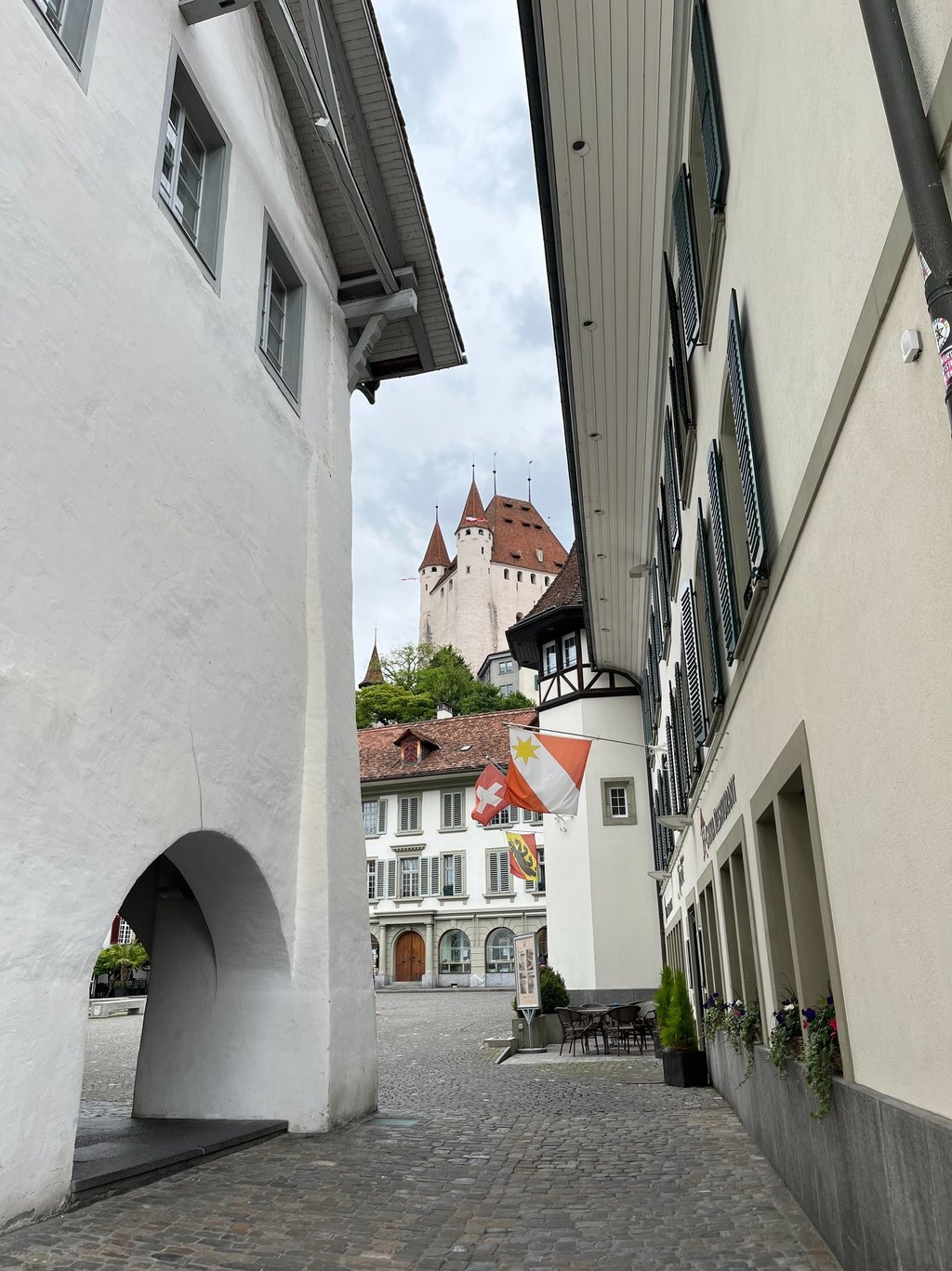 View of Thun Castle, the Thun city flag, the Swiss flag, and the flag of the Canton of Bern