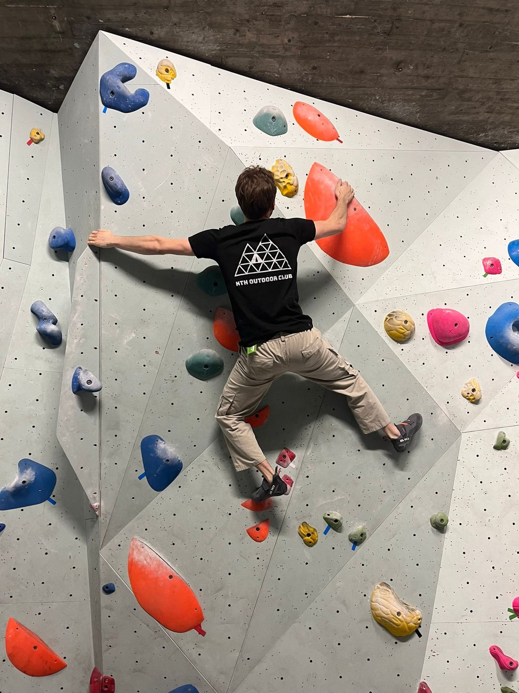 a man is bouldering on a wall in a climbing gym