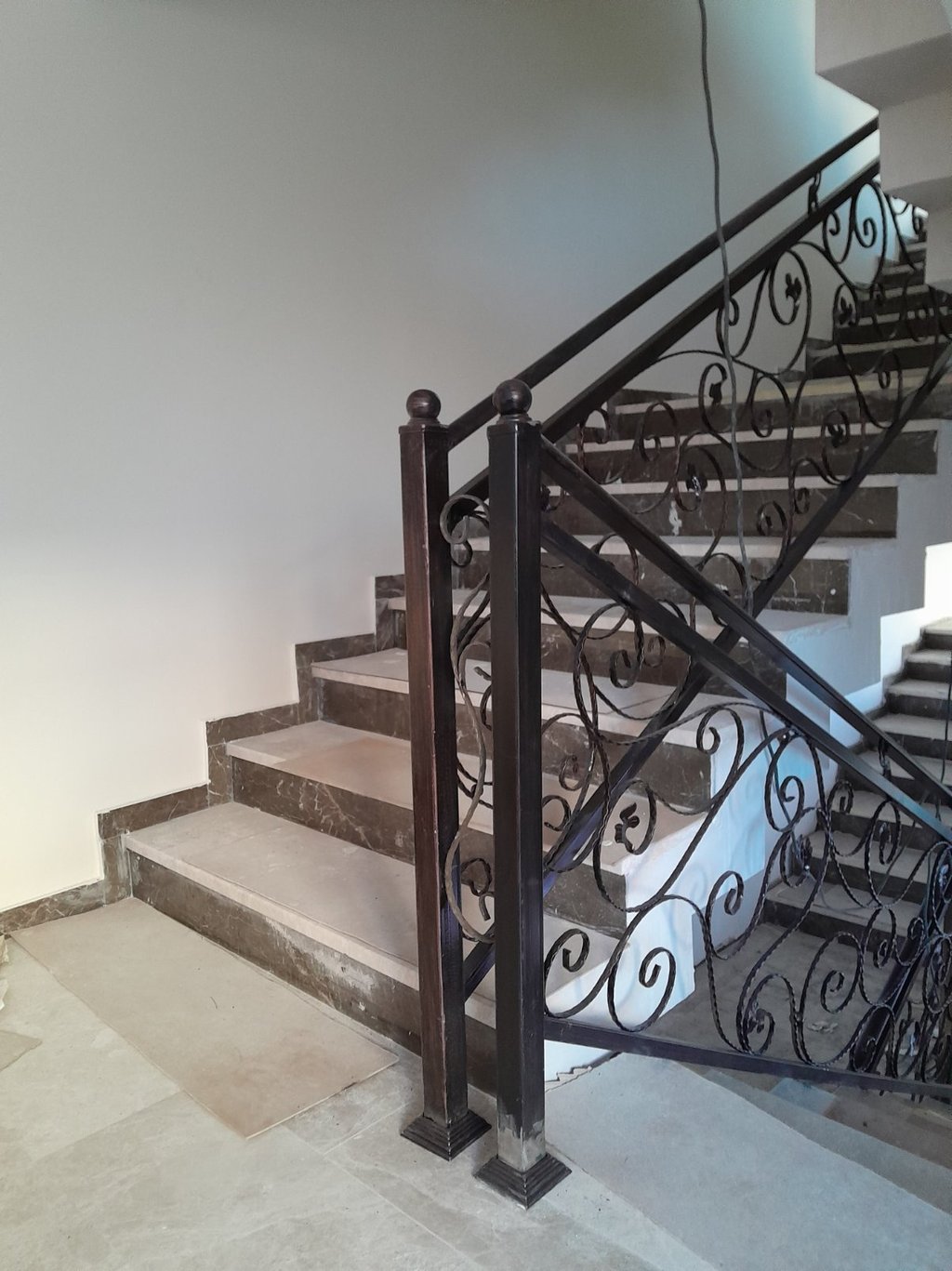 Elegant marble staircase featuring custom wrought iron railings with decorative scrollwork.