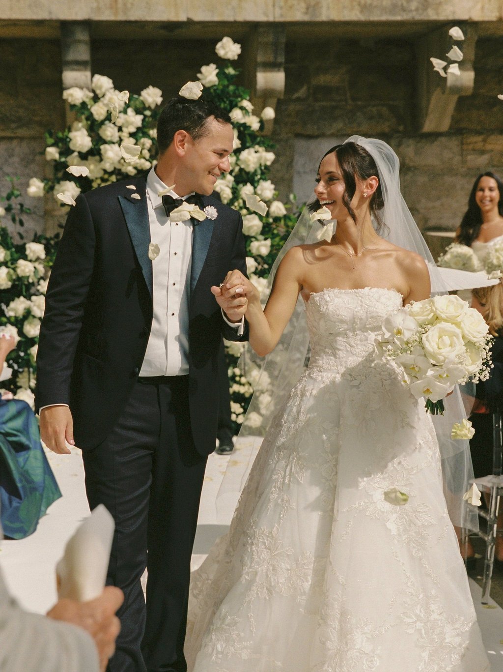 Happy just married couple walking down the aisle full of white flowers