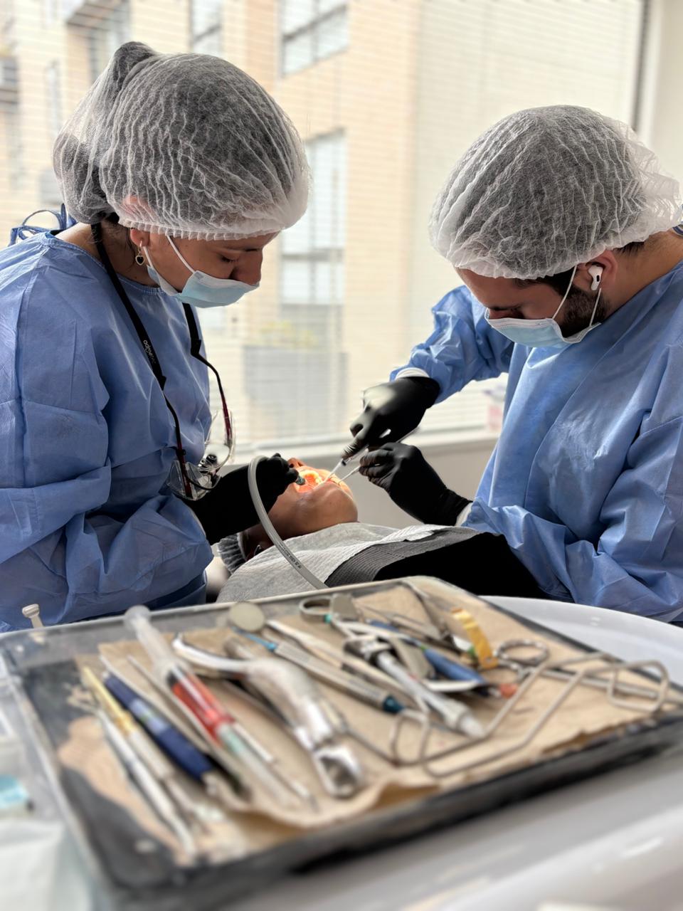 Professional dentists perform a dental procedure on a patient using specialized tools.