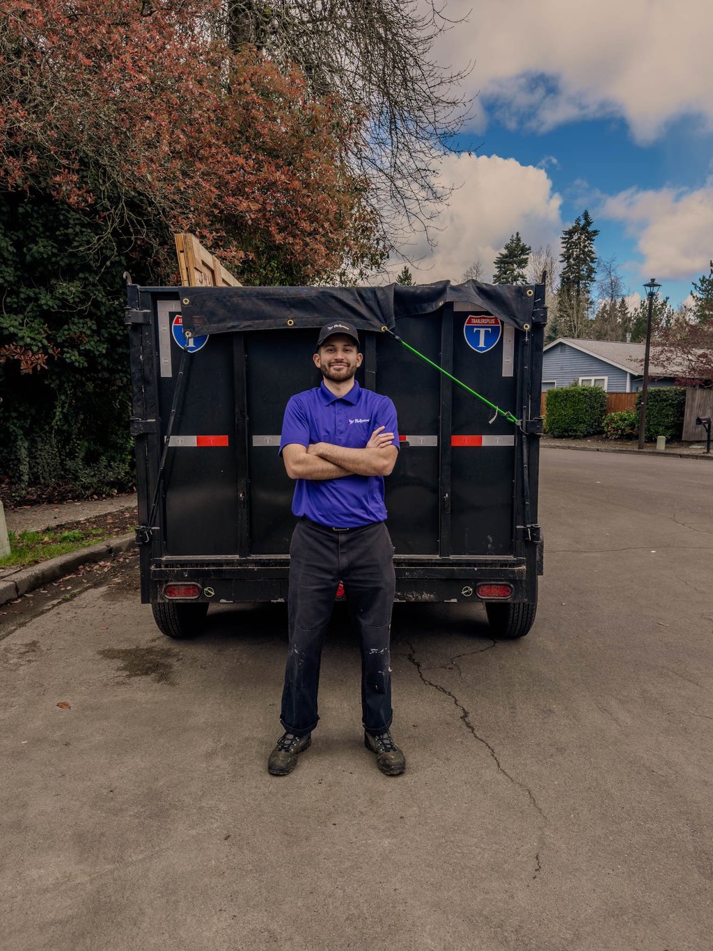 Professional junk removal service worker standing in front of a black dump trailer in Portland OR