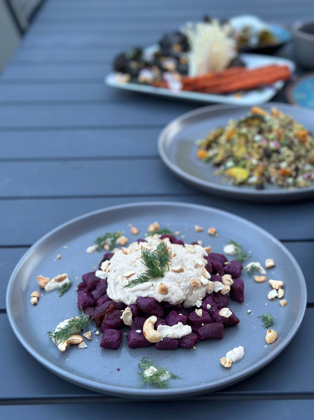 a plate of beetroot gnocchi on a table with a plate of food
