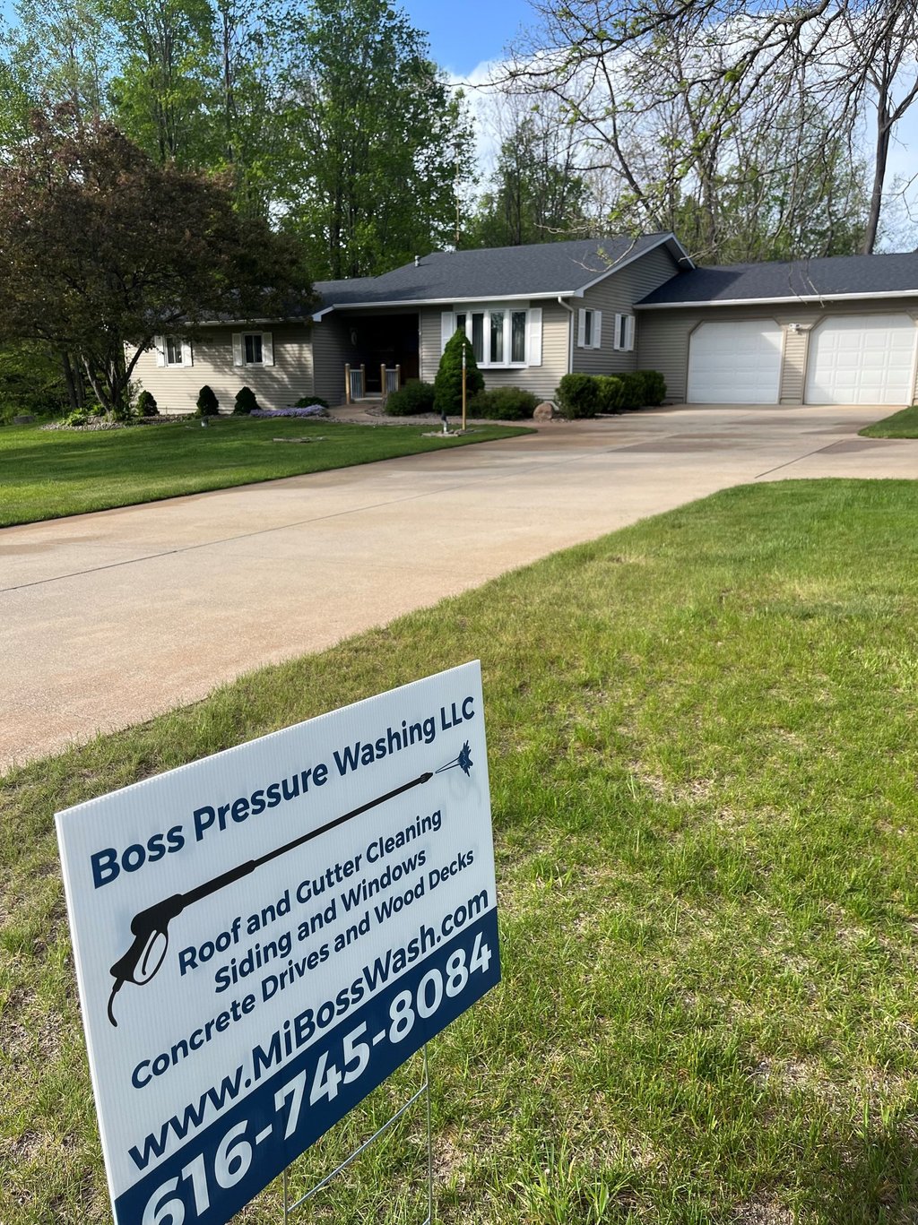 Boss Pressure Washing LLC yard sign in front of a freshly cleaned driveway and home.