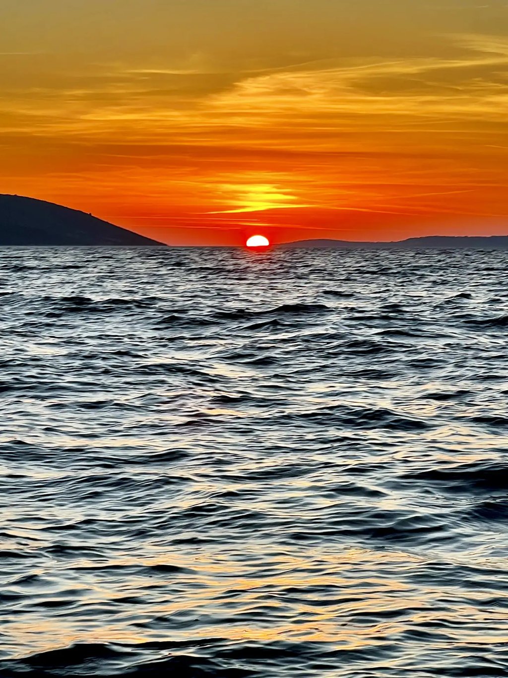 Dramatic Adriatic sunset with island silhouettes and the sun about to dip into the sea photographed from a boat