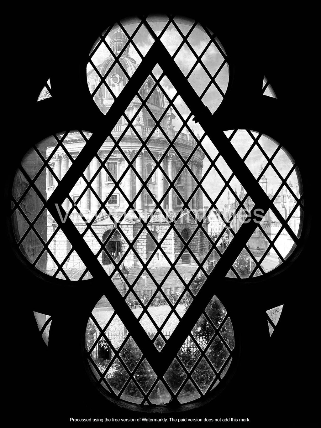 Black and white view of the Radcliffe Camera in Oxford through a gothic quatrefoil window.