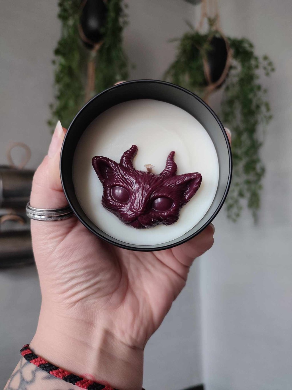 Bougies à la cire blanche, avec un fondant en forme de chat cornu, bordeaux. Contenant en métal noir