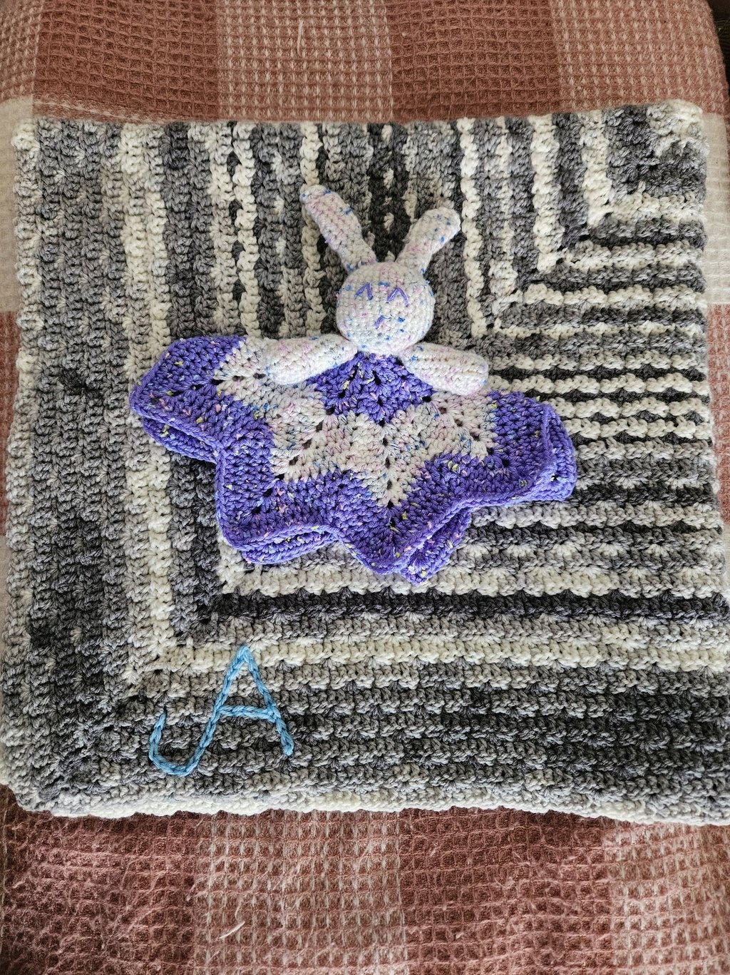 a crocheted rabbit lovey on a crochet blanket