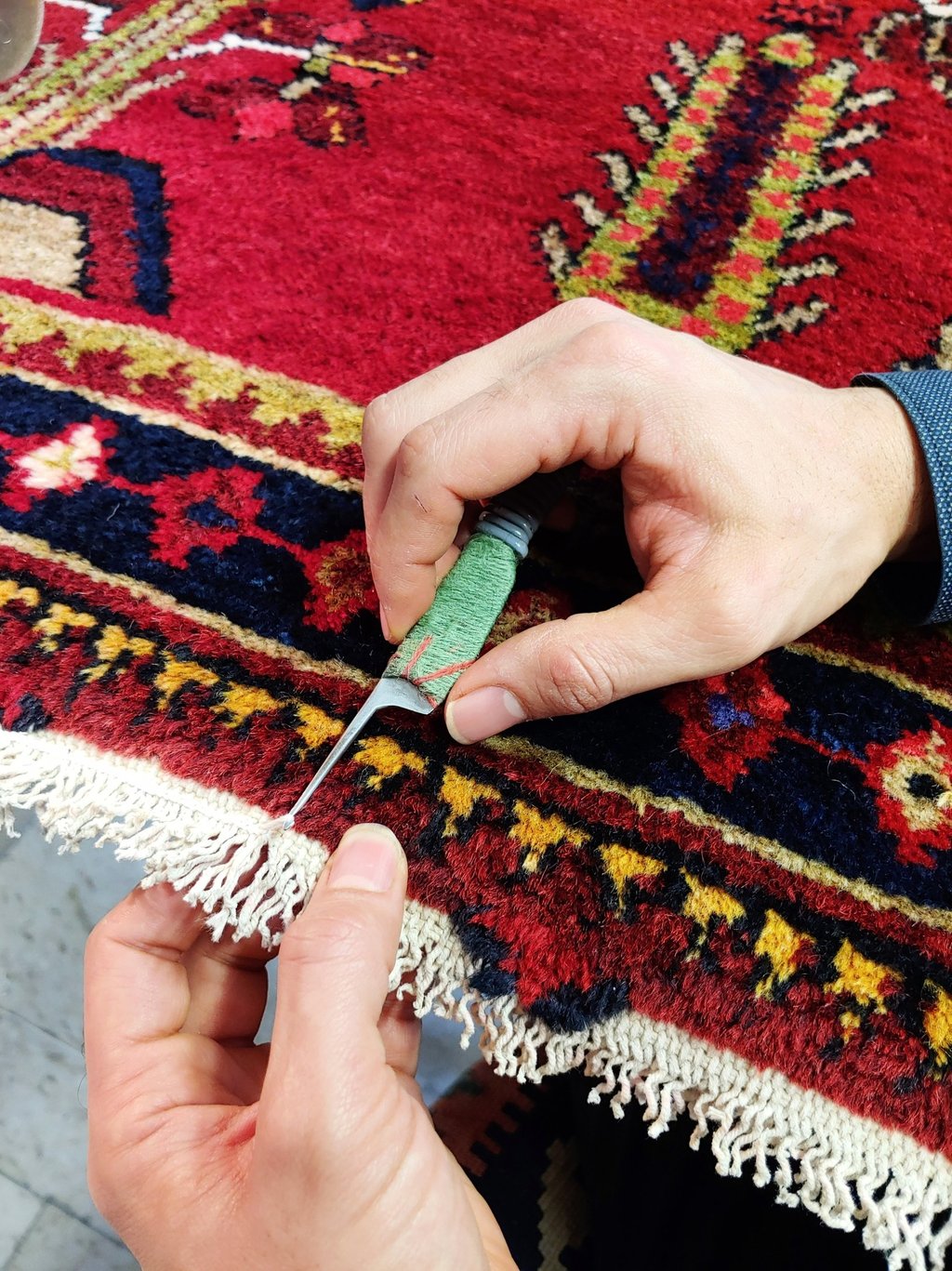 restauratore di tappeti che realizza la chiusura delle frange a uncinetto