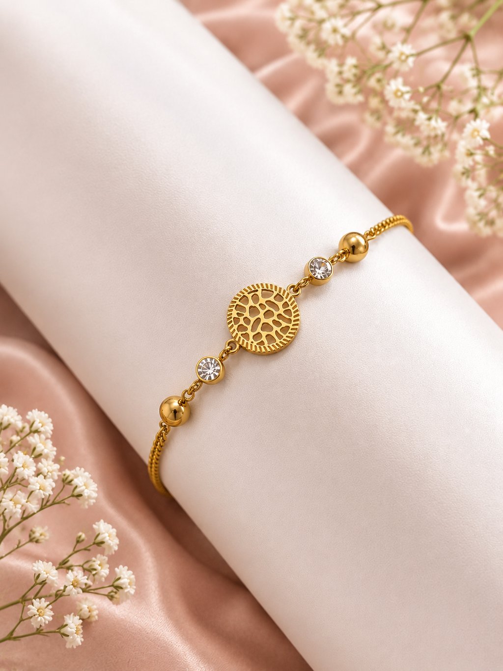 Elegant gold filigree bracelet with crystal accents displayed on a white stand with baby's breath flowers.